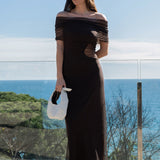 Isabella con el vestido First Step chocolate, luciendo el chal de tul sobre los hombros y bolso de mano blanco.