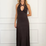 Modelo con vestido marrón chocolate, confeccionado en un tejido de licra con cuerpo que se adapta a la figura. Su escote halter y las delicadas piezas de tul en el cuello y la espalda abierta le dan un toque romántico y sutil.
La falda midi, con godetes que le aportan un movimiento fluido y ligero.