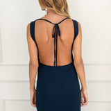 Modelo con vestido largo azul noche de silueta fluida con escote drapeado y espalda descubierta. Su tejido en gasa realza la figura con elegancia. Ideal para invitadas y eventos de otoño.
