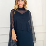 Modelo con vestido largo azul noche de silueta fluida con escote drapeado y espalda descubierta. Su tejido en gasa realza la figura con elegancia. Ideal para invitadas y eventos de otoño.