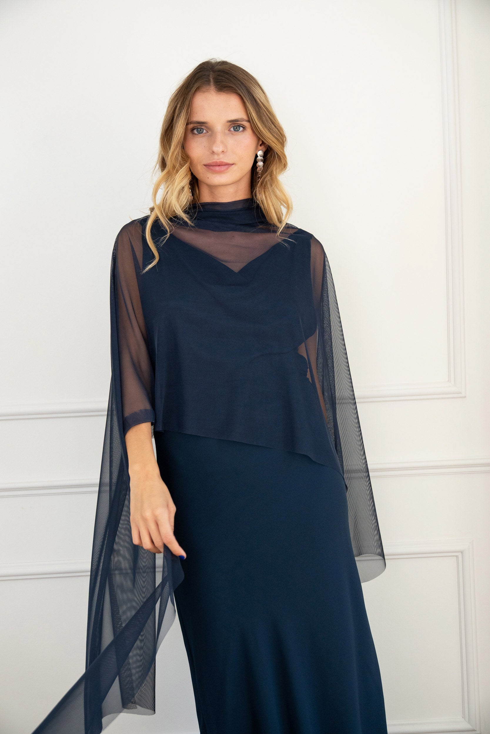 Modelo con vestido largo azul noche de silueta fluida con escote drapeado y espalda descubierta. Su tejido en gasa realza la figura con elegancia. Ideal para invitadas y eventos de otoño.
