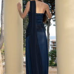 Vista trasera de Isabella con el vestido azul noche, luciendo la tira larga cruzada para resaltar la espalda descubierta.