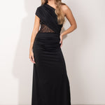 Modelo con vestido largo negro asimétrico, con detalle de encaje semitransparente en el torso y falda recta