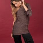 Modelo posando con Vestido asimétrico corto en color cobre brillante. Combinado con pantalones satinados negros.