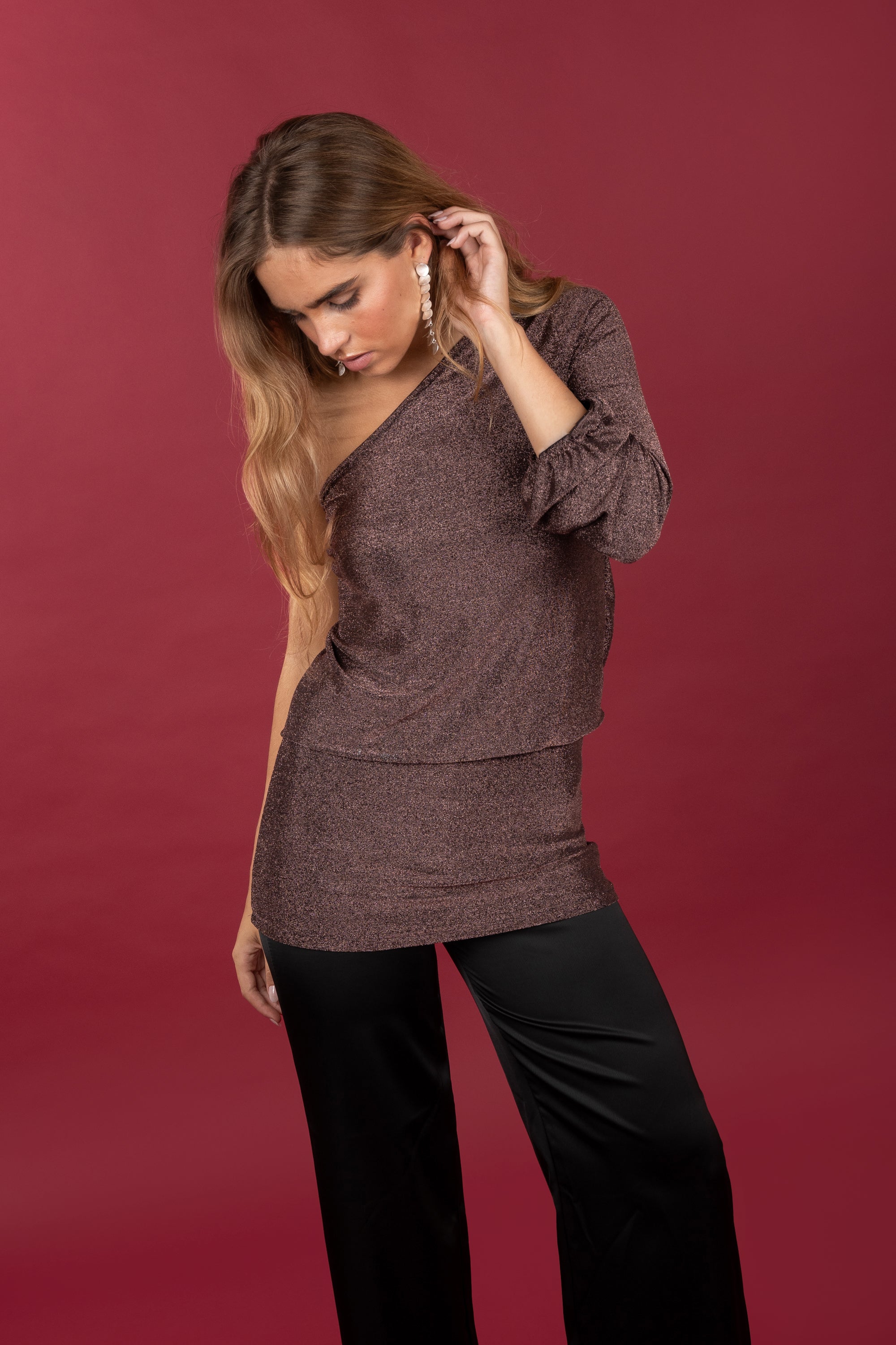 Modelo posando con Vestido asimétrico corto en color cobre brillante. Combinado con pantalones satinados negros.