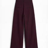 Pantalón berenjena de corte holgado con pliegues y doble hebilla para mujer, mostrado de espaldas sobre fondo blanco neutro.