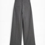 Pantalón gris de corte holgado con pliegues delanteros y doble hebilla para mujer, mostrando la vista trasera sobre fondo blanco neutro.
